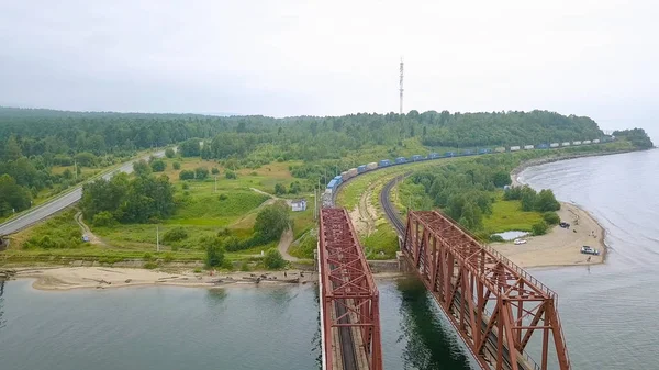 Ryssland, Bajkal - 02 augusti 2018: Transsibiriska järnvägen, kusten av Lake Baikal. Rörligheten för tåg på iron bridge över floden flyter in Baikal, från Drone — Stockfoto