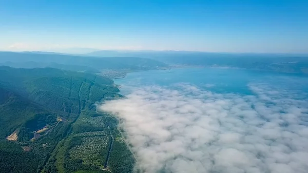 Flying above the clouds. Coast of Lake Baikal. Mountains covered with forest. Russia, From Drone — Stock Photo, Image