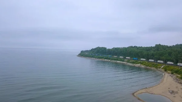 Rusia, Baikal - 02 de agosto de 2018: Trans-Siberian Railway, coast of Lake Baikal. Movimiento del tren a lo largo de la orilla del lago, Desde Drone —  Fotos de Stock