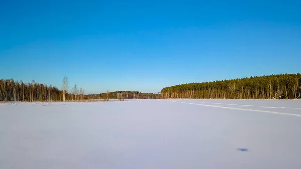 Basso volo sulla neve con tracce. Lago ghiacciato. Ombra dal drone. Tempo limpido invernale, Da Drone — Foto Stock