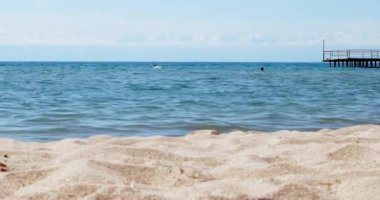 Aksaklık etkisi. Dağların arka planda Issyk-Kul Gölü'nde insanlar, Cholpon Ata sahil kasabası, Kırgızistan. Video. Ultrahd (4k))