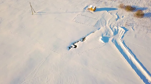 Campo cubierto de nieve con un punto descongelado del arroyo. Rastros de animales salvajes. Invierno clima claro, Desde Drone — Foto de Stock
