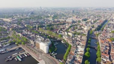 Amsterdam, Hollanda. Amsterdam Merkez İstasyonu (Amsterdam Centraal) doğru şehir çatıları üzerinde uçan. 4k