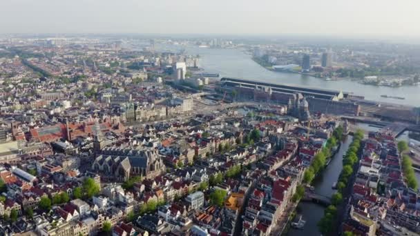 Amsterdam, Nederländerna. Flyger över stadens hustak mot Amsterdams centralstation (Amsterdam Centraal) och runt Oudekerks kyrka (De Oude Kerk). 4K — Stockvideo