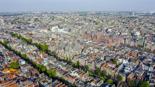 Amsterdam, Nizozemsko. Létání nad městskými střechami směrem k amsterdamské centrální stanici (Amsterdam Centraal) a kolem kostela Oudekerk (De Oude Kerk), letecký pohled — Stock fotografie