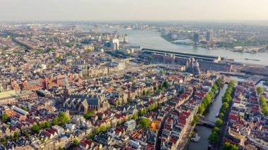 Amsterdam, Hollanda. Amsterdam Merkez İstasyonu (Amsterdam Centraal) ve Oudekerk kilisesi (De Oude Kerk ) etrafında doğru şehir çatıları üzerinde Uçan , Havadan Görünümü 