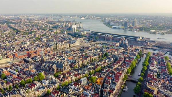 Amszterdam, Hollandia. Repül át a város háztetőkön felé Amsterdam Central Station (Amsterdam Centraal), és az egész Oudekerk templom (de Oude Kerk), a légi nézet — Stock Fotó