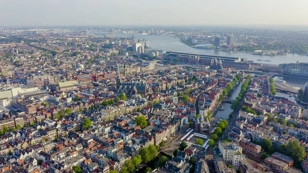 Amsterdam, Hollanda. Amsterdam Merkez İstasyonu (Amsterdam Centraal) doğru şehir çatıları üzerinde Uçan , Havadan Görünümü — Stok fotoğraf