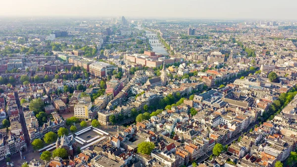 Amsterdam, Nizozemsko. Létání nad městskými střechami směrem k hlavnímu nádraží Amsterdamu (Amsterdam Centraal), letecký pohled — Stock fotografie