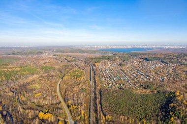 Yol demiryoluna paralel gidiyor. Tatil köyleri. Günbatımında karışık ormanın üzerinde uçmak. Ural, Rusya. Uzakta Yekaterinburg şehri görülebilir.