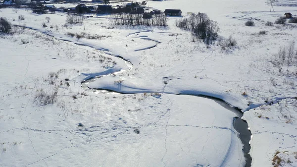 在冬季飞越一片森林覆盖的沼泽地 小河在雪地里 空中风景 — 图库照片