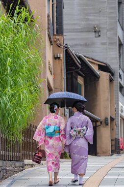 Geleneksel elbise giyen kadınlar Japonya 'nın Kyoto kentindeki geleneksel binaların etrafında yürüyor