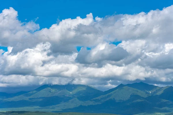 Low clouds over summer mountains green grass and blue sky landscape