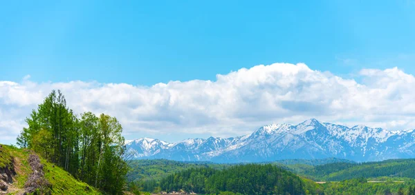 Paisaje rural panorámico con montañas. Gran cielo azul y nubes blancas sobre el campo de cultivo en un hermoso día soleado en primavera . — Foto de Stock