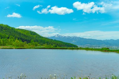 Bahar mevsiminde güzel güneşli bir günde, büyük mavi gökyüzü ve beyaz bulutlar. Dağlar ile panoramik kırsal manzara.