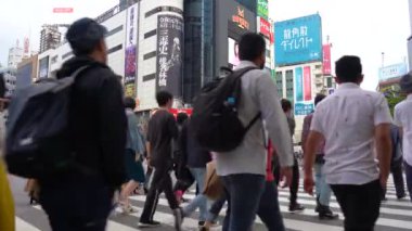 Tokyo, Japonya - 4 Mayıs 2019 : Shibuya Geçidi'nde gündüz yürüyen yaya ( 4k Uhd Düşük Açı ). Shibuya semtinde normal hızda yayaların yaya geçidi görünümü