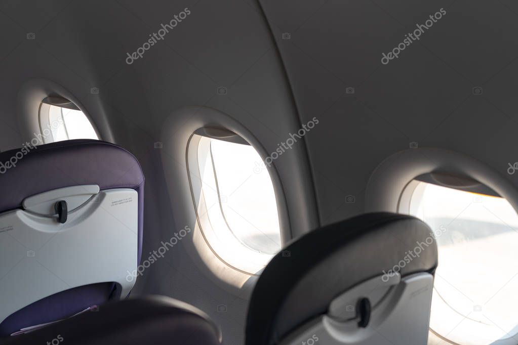 Airplane seats in the cabin economy class and the windows of the airplane. A view of porthole window on board an airbus for your travel concept or passenger air transportation.