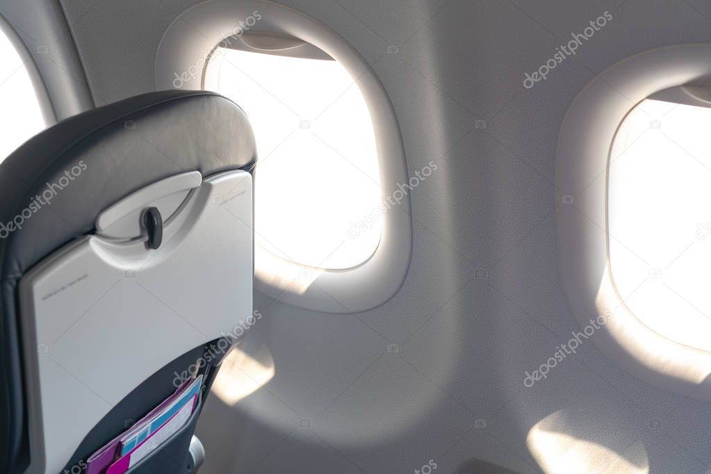 Airplane seats in the cabin economy class and the windows of the airplane. A view of porthole window on board an airbus for your travel concept or passenger air transportation.