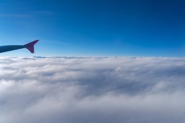 Havada, uçak penceresinden görüntülenen, koyu mavi gökyüzü ufku ve güneş doğma süresi bulut arka plan ile uçak kanat siluetgörünümü