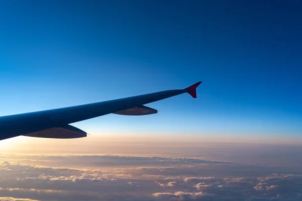 Arriba en el aire, vista de la silueta del ala del avión con el horizonte azul oscuro del cielo y el fondo de la nube en el tiempo de salida del sol, visto desde la ventana del avión —  Fotos de Stock