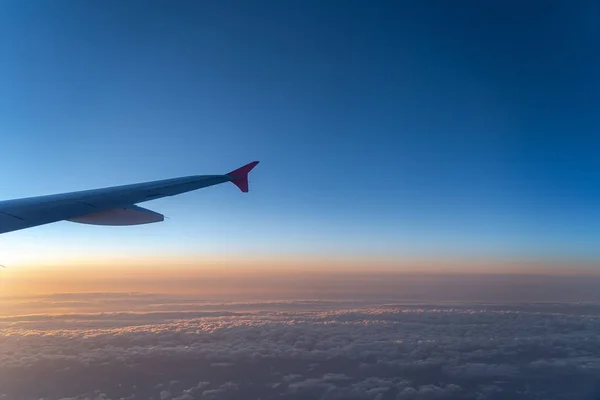 Arriba en el aire, vista de la silueta del ala del avión con el horizonte azul oscuro del cielo y el fondo de la nube en el tiempo de salida del sol, visto desde la ventana del avión —  Fotos de Stock