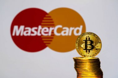 Arka plan ekranında Mastercard logosu olan Altın Bitcoin sikkeleri. Tokyo, Japonya - 12 Temmuz 2019