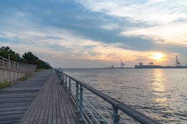 Yaz güneşi set zaman arka planda Yumeshima ada ile Osaka koyu, Osaka metro Cosmosquare tren istasyonu park gezinti görünümü