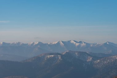 Güzel dağ manzara panoramik görünümü, ilkbahar güneşli bir günde koyu mavi berrak gökyüzü arka plan ile orman kaplı karlı dağ zirveleri