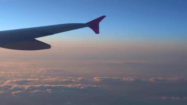 在空中 从飞机窗口看 在太阳升起时 有深蓝色天空地平线和云背景的飞机机翼剪影 — 图库视频影像