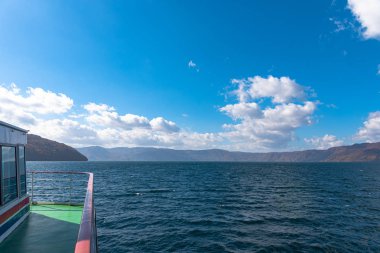 Lake Towada Gezi Turları. Güzel görünümü, berrak mavi gökyüzü, beyaz bulut, sonbahar yeşillik sezon arka plan ile güneşli bir günde yolcu gemisi. Towada hachimantai Ulusal Parkı, Aomori Prefecture, Japonya