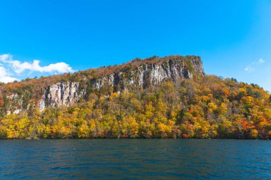 Güzel sonbahar yeşillik manzara manzaralar. Sonbahar muhteşem renklerle doludur. Towada Gölü gezi Cruise gemi görünümü. Berrak mavi gökyüzü, su, beyaz bulut, güneşli bir gün arka plan. Aomori, Japonya