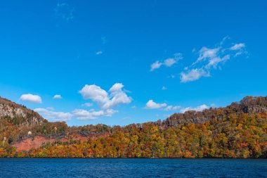 Güzel sonbahar yeşillik manzara manzaralar. Sonbahar muhteşem renklerle doludur. Towada Gölü gezi Cruise gemi görünümü. Berrak mavi gökyüzü, su, beyaz bulut, güneşli bir gün arka plan. Aomori, Japonya