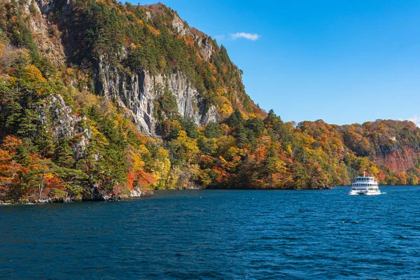 Lake Towada Gezi Turları. Güzel görünümü, berrak mavi gökyüzü, beyaz bulut, sonbahar yeşillik sezon arka plan ile güneşli bir günde yolcu gemisi. Aomori, Japonya. Gemide Japonca Metin 