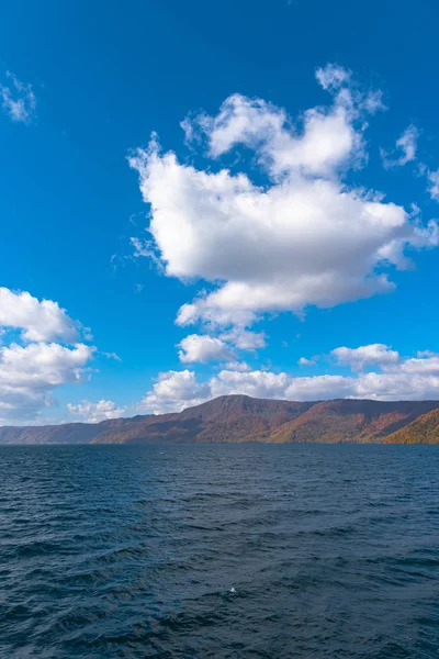 Hermosos paisajes de follaje otoñal. El otoño está lleno de magníficos colores. Vista desde la orilla del lago Towada, cielo azul claro y agua, nube blanca, fondo de día soleado. Prefectura de Aomori, Japón —  Fotos de Stock