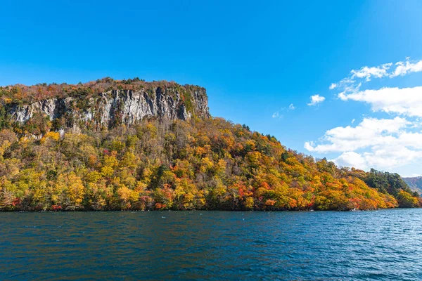 美しい紅葉風景。秋は壮大な色でいっぱいです。十和田湖観光クルーズ船からの眺め。澄んだ青い空、水、白い雲、晴れた日の背景。青森県 — ストック写真