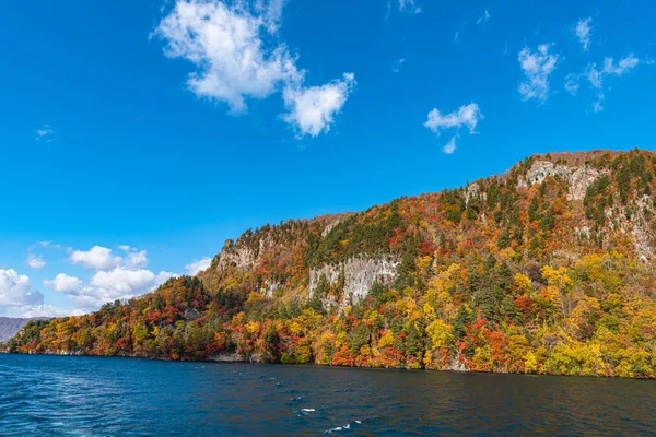 美しい紅葉風景。秋は壮大な色でいっぱいです。十和田湖観光クルーズ船からの眺め。澄んだ青い空、水、白い雲、晴れた日の背景。青森県 — ストック写真