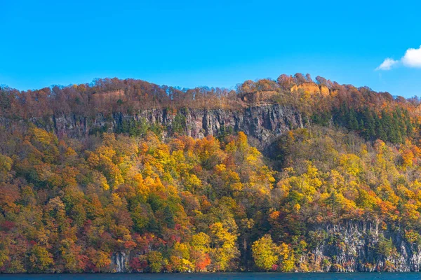 美しい紅葉風景。秋は壮大な色でいっぱいです。十和田湖観光クルーズ船からの眺め。澄んだ青い空、水、白い雲、晴れた日の背景。青森県 — ストック写真