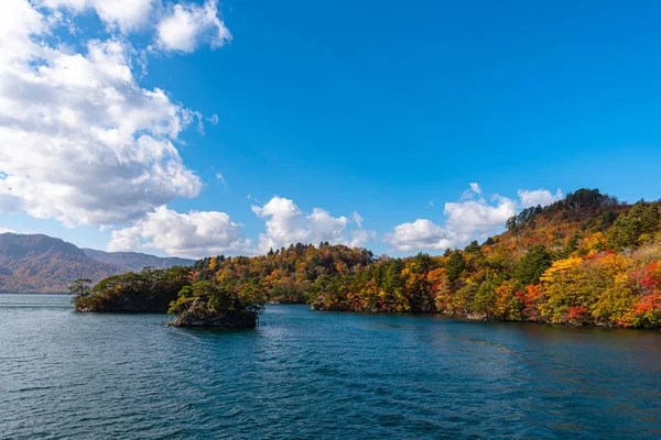Güzel sonbahar yeşillik manzara manzaralar. Sonbahar muhteşem renklerle doludur. Towada Gölü gezi Cruise gemi görünümü. Berrak mavi gökyüzü, su, beyaz bulut, güneşli bir gün arka plan. Aomori, Japonya — Stok fotoğraf