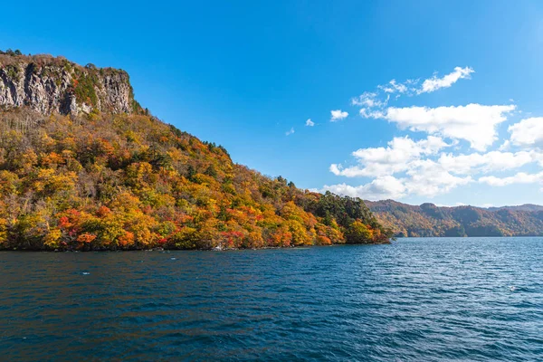 美しい紅葉風景。秋は壮大な色でいっぱいです。十和田湖観光クルーズ船からの眺め。澄んだ青い空、水、白い雲、晴れた日の背景。青森県 — ストック写真