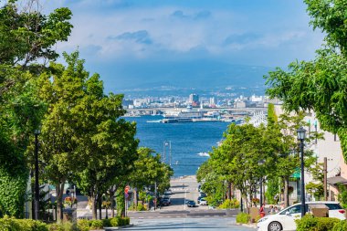 Hakodate, Hokkaido, Japonya - 15 Temmuz 2018: Güneşli yaz günlerinde Hachiman-zaka yamacının manzarası beyaz bulutlar ve bule gökyüzü. Eğik bir cadde, filmlerde ve reklamlarda ünlü oldu. Popüler Manzara Mekanı