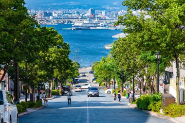Hakodate, Hokkaido, Japonya - 15 Temmuz 2018: Güneşli yaz günlerinde Hachiman-zaka yamacının manzarası beyaz bulutlar ve bule gökyüzü. Eğik bir cadde, filmlerde ve reklamlarda ünlü oldu. Popüler Manzara Mekanı