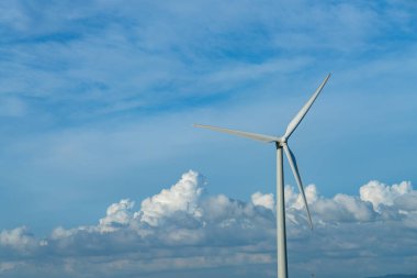Güneşli bir günde mavi gökyüzü ve beyaz bulutlarla yakın çekim rüzgar türbinleri veya rüzgar enerjisi dönüştürücüsü