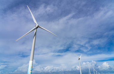 Güneşli bir günde mavi gökyüzü ve beyaz bulutlarla yakın çekim rüzgar türbinleri veya rüzgar enerjisi dönüştürücüsü