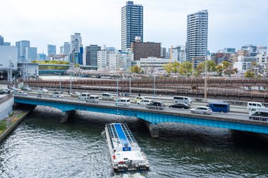 Osaka, Japonya - 8 Nisan 2025: Baharda Kema Sakuranomiya Parkı 'ndaki kiraz çiçeği festivali sırasında Okawa Nehri üzerinde turist gezisi teknesi.