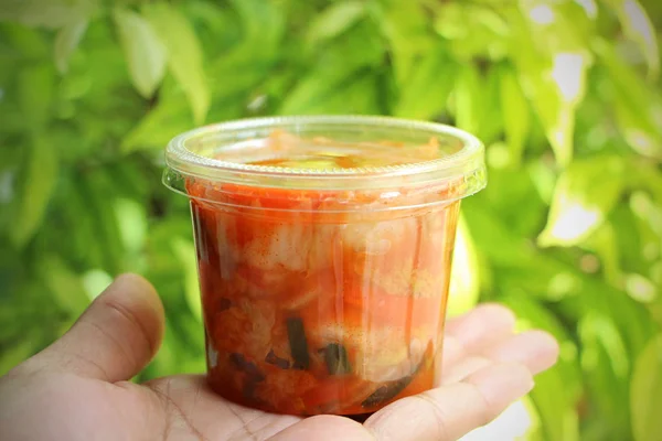 Kimchi korean food in the package plastic on the hand has a natural background.