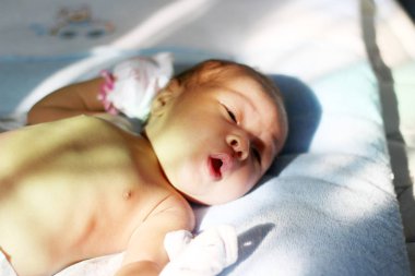 Güneş ışığında yatakta yatan bir bebek, sabah güneşlenmek, sabah güneşi yenidoğan sağlığı için iyi.