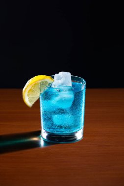 Koyu arkaplanda limonla süslenmiş Mavi Göl Kokteyli