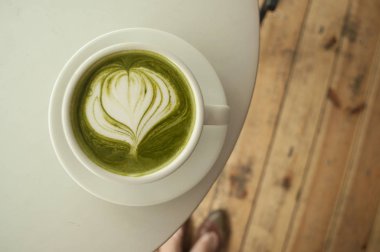 Matcha çay güzel latte sanat bir kafede gri bir tablo ile.