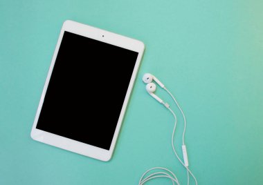 Çalışma yeri düz yatıyordu. Tablet ve mavi arka plan üzerinde kulaklık.