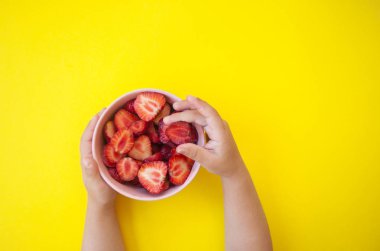 Pembe kase parlak sarı zemin üzerine güzel taze sulu çilek metin alanı ile dolu holding çocuğun eller.